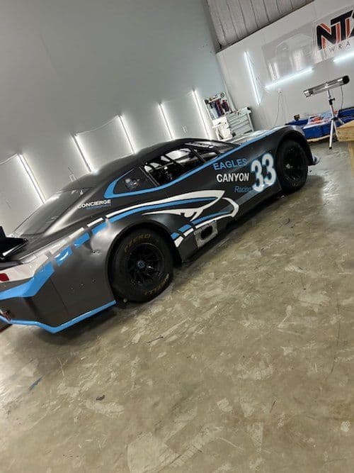A race car with the number 33 on the side is parked in a garage