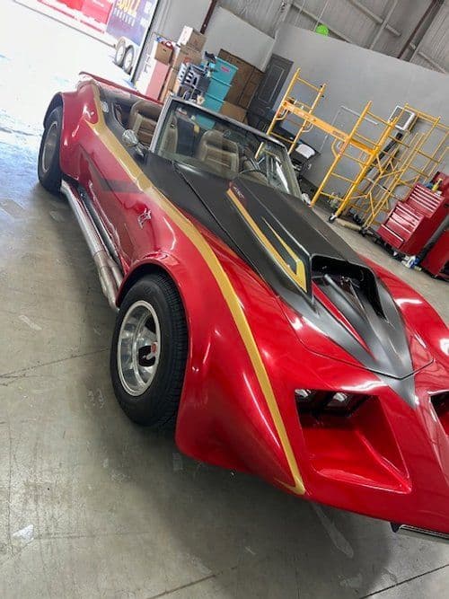 A red sports car is parked in a garage