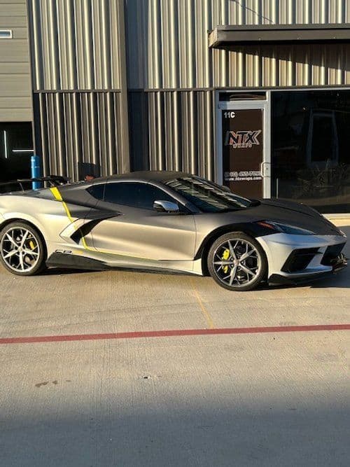 A silver sports car is parked in front of a building