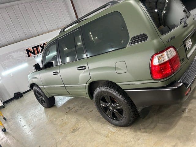 A green toyota land cruiser is parked in a garage