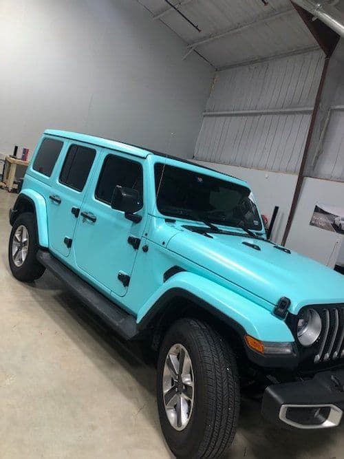 A blue jeep is parked in a garage