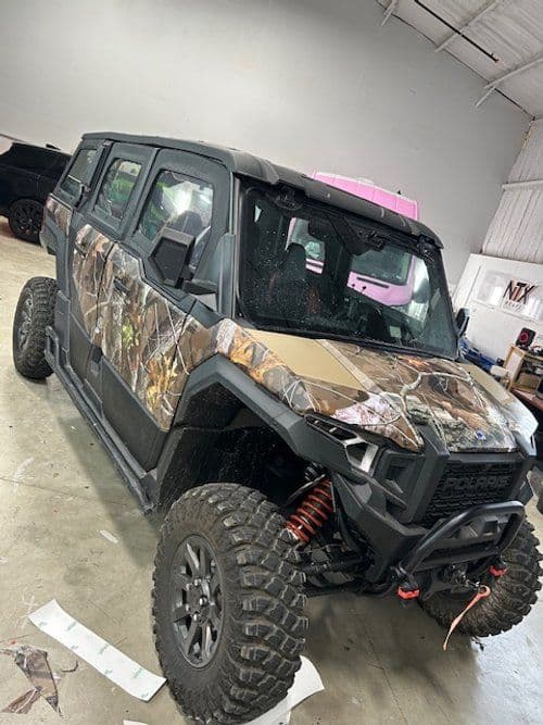 A camouflage covered atv is parked in a garage