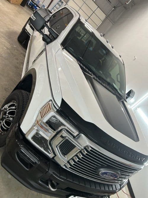 A white ford truck is parked in a garage