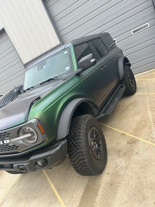A black and green ford bronco is parked in a parking lot