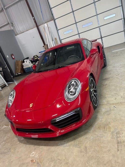 A red porsche 911 turbo s is parked in a garage