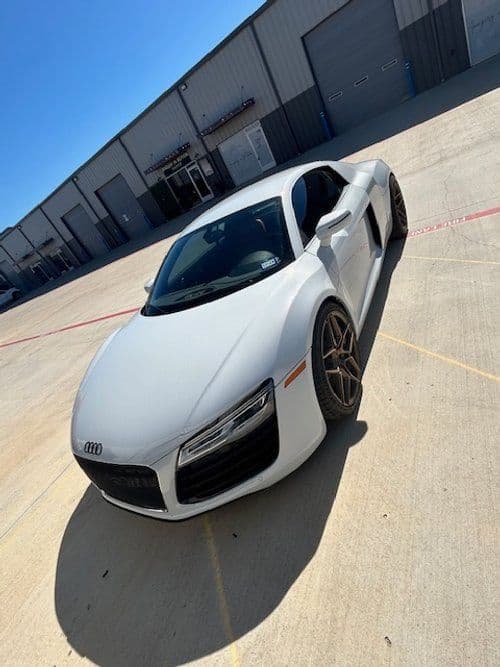 A white audi r8 is parked in a parking lot